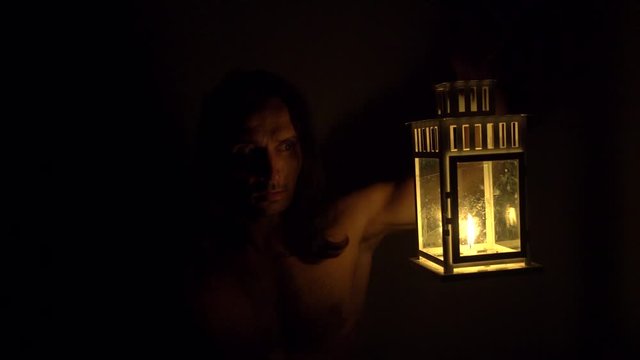 halloween, a man looks at himself in the mirror holds a lamp with candles in his hands, he is scared