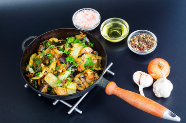 Fried eggplant, paprika and different vegetables in pan on black background