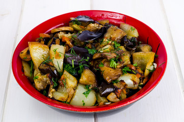 Vegetable saute with eggplants in ceramic bowl on white wooden table