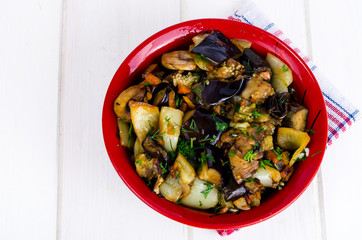 Vegetable saute with eggplants in ceramic bowl on white wooden table