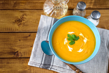 Top view of pumpkin soup with cream in blue plate and parsley