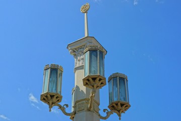 Fototapeta na wymiar white post with three retro lanterns on a background of blue sky