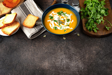 Top view of pumpkin soup and bread on dark vintage wooden background