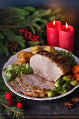 Baked ham with vegetables: potatoes, carrots, brussel sprouts, cabbage and green peas. Christmas decorations. Dish for Christmas Eve
