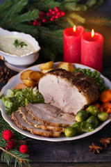 Baked ham with vegetables: potatoes, carrots, brussel sprouts, cabbage, green peas and sauce. Christmas decorations. Dish for Christmas Eve