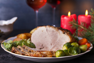 Baked ham with vegetables, two glasses of red wine. Christmas decorations. Dish for Christmas Eve