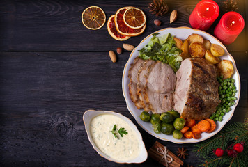 Baked ham with vegetables: potatoes, carrots, brussel sprouts, cabbage and green peas. Christmas decorations. Dish for Christmas Eve. View from above, top studio shot, room for text