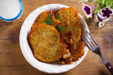 Potato pancakes with fried pork belly and onion in bowl - overhead, horizontal