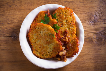 Potato pancakes with fried pork belly and onion in bowl - overhead, horizontal