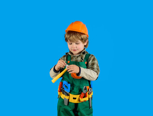 Little repairman with tool belt. Little boy in builder's uniform with hammer. Tools for building. Builder boy in helmet and tools. Child game. Work with tools. Repair. Kid boy as builder or repairer.