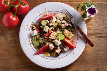 Healthy vegetarian food: tomato, cucumber, lettuce and mushroom salad with feta cheese and walnuts. View from above, top studio shot