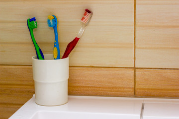 Toothbrushes stand on the sink on bathroom wall