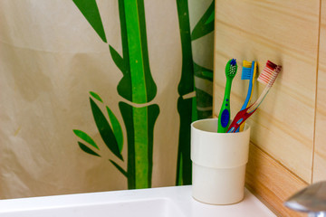 Toothbrushes stand on the sink on bathroom wall