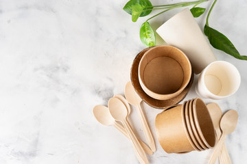 Eco tableware on light green background. Paper and bamboo cups, bag and wooden cutlery