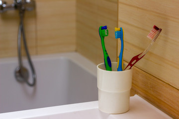 Toothbrushes stand on the sink on bathroom wall