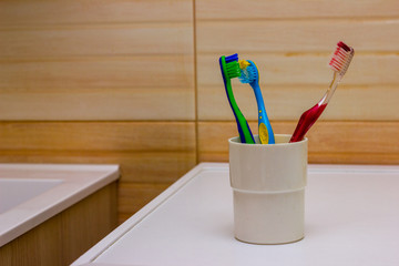 Toothbrushes stand on the sink on bathroom wall