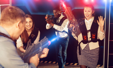 Men and women in business suits playing laser tag emotionally in