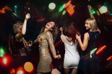 New Year, birthday, 8 march dance party. Happy friends company with drinks, Christmas celebration, modern youth life. Women enjoying night out at bar dancing in disco lights.