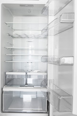 Interior of an open empty branch new refrigerator with shelves compartments for ergonomic food storage. Home kitchen electrical appliances concept