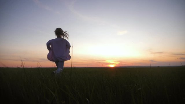 Little girl is running on meadow at sunset time. The concept of childhood dreams or the desire to move forward.