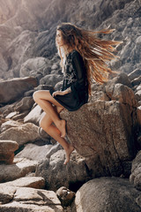beautiful young woman posing on the stone beach