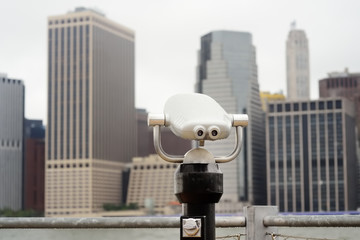 Binoculars looking to the Manhattan skyline over East River at rainy day.
