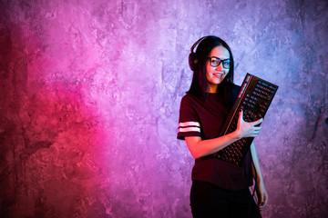 Young teen gamer wearing glasses standing posing with computer gaming equipment