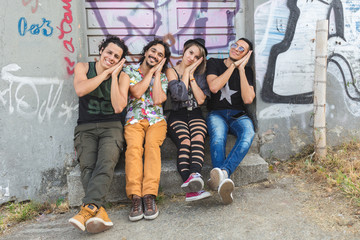 Obraz na płótnie Canvas personas jóvenes sentadas en la calle con graffitis 