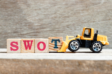 Toy bulldozer hold letter block T to complete word swot (abbreviation of strength, weakness,...
