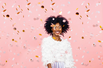 Happy woman with a big smile and confetti falling, on pink background
