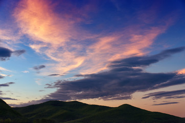 Dramatic sunset and sunrise sky with beautiful pink, yellow and blue clouds over the mountains