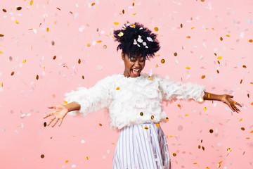 Young woman smiling with arms open amid confetti falling