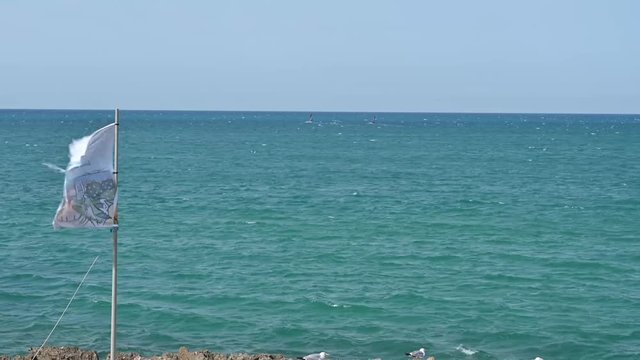 Bandiera in riva al mare sventola per il forte vento