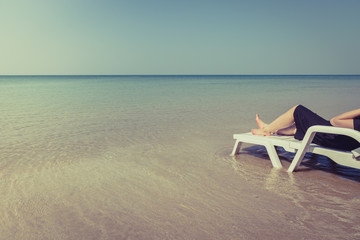 Vacation on tropical beach Woman's legs on the beach bed with clear ocean water