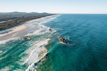 Aerial of a beach with waves at sunset with nice tones and warm summer vibes.
