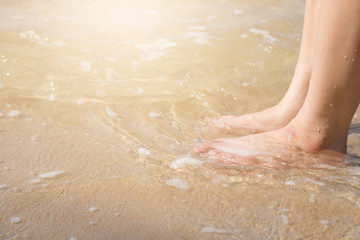 woman foot on the sand beach with sea water