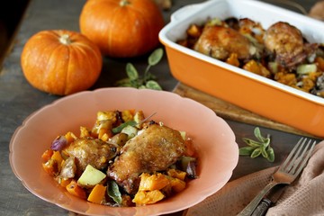 baked chicken with pumpkin and potatoes and sage. chicken pieces on a cushion of vegetables. autumn dish. orange colors. space for copy. place for text. top view
