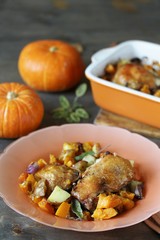 baked chicken with pumpkin and potatoes and sage. chicken pieces on a cushion of vegetables. autumn dish. orange colors. space for copy. place for text. top view
