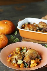 baked chicken with pumpkin and potatoes and sage. chicken pieces on a cushion of vegetables. autumn dish. orange colors. space for copy. place for text. top view