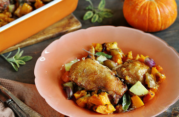 baked chicken with pumpkin and potatoes and sage. chicken pieces on a cushion of vegetables. autumn dish. orange colors. space for copy. place for text. top view