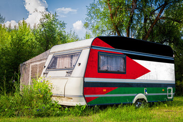 A car trailer, a motor home, painted in the national flag of  Jordan stands parked in a mountainous. The concept of road transport, trade, export and import between countries.