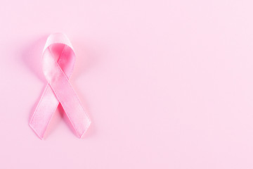 Pink ribbon on pink pastel paper background for supporting breast cancer awareness month campaign.
