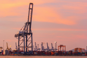 Obraz premium Cargo cranes in industrial port at sunset.