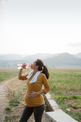 thirsty pregnant woman after workout drinking a bottle of water