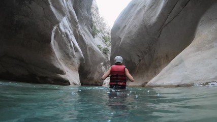 Woman in safety jacket enjoying extreme adventure hiking canyon river national park.