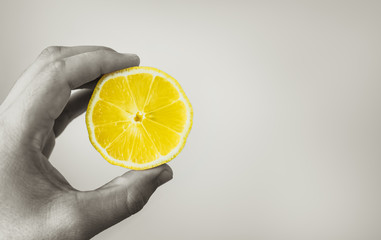 Hand holding up slice of lemon isolated