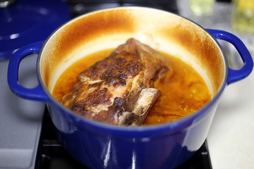Braised pork roast cooked in a Dutch oven resting on the stove top.