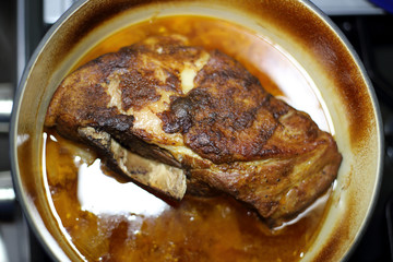 Braised pork roast cooked in a Dutch oven resting on the stove top.