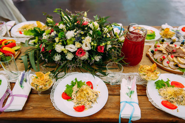 Beautifully served banquet table decorated with fresh flowers with a variety of snacks and salads at the wedding celebration.