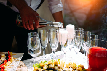 Welcome drink at the gala event. The waiter pours champagne into glasses, close-up.